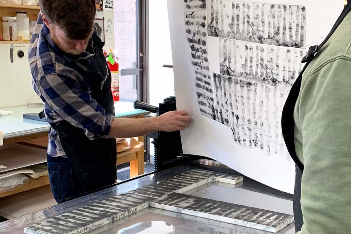 Printers Brian Berry and Steven Fournier pulling the monoprint from the etching press.