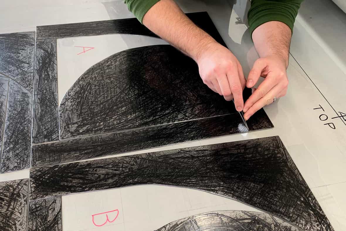 Printer Steven Fournier adjusting plate registration to print the etching.