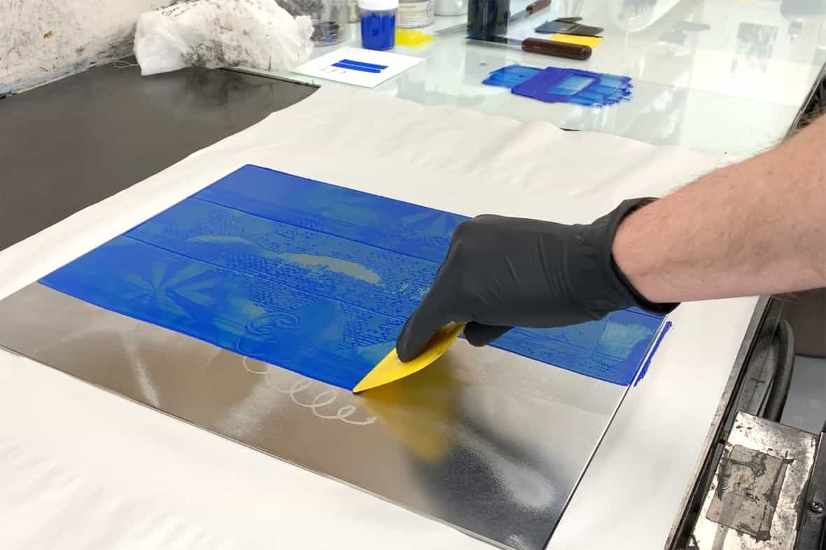 Printer Michael Rahn carding ink onto an etching plate.