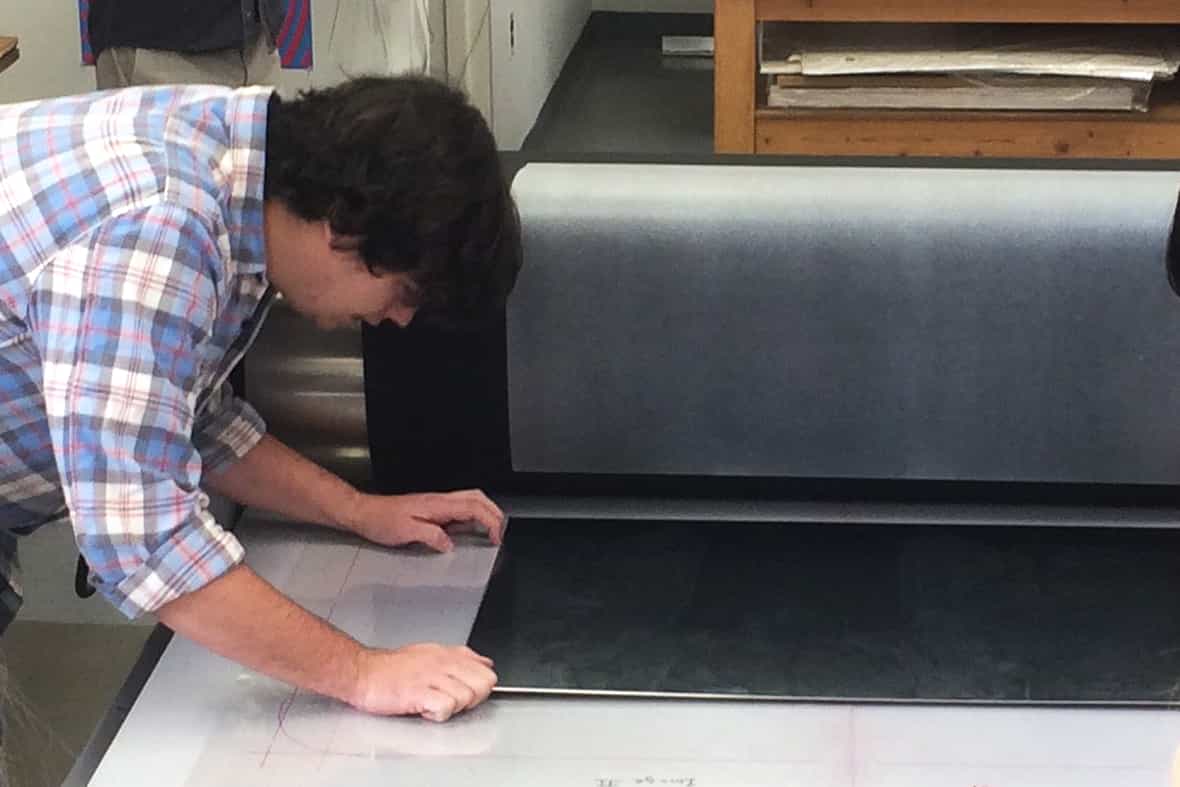 Printmaker Steven Fournier preparing to print the etching plate on the black paper with chine-collé for Jasper Johns "Regrets."